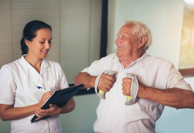 Senior man with dumbbells in rehab with a physiotherapist