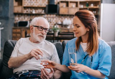 Nurse giving a glass of water to patient with pills