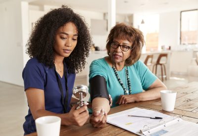 Female healthcare worker checking the blood pressure of a senior woman during a home visit