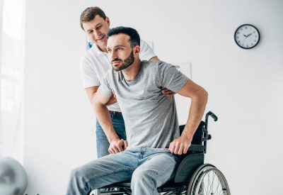 Physiotherapist helping handicapped man in Wheelchair during recovery in hospital