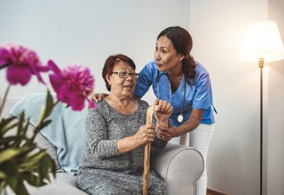 Caregiver, carer hand holding elder hand woman in hospice care. Philanthropy kindness to disabled concept.Public Service Recognition Week. Attentive young doctor talks with female patient
