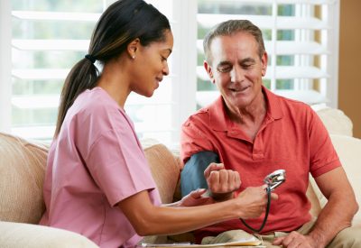 Nurse Visiting Senior Male Patient At Home