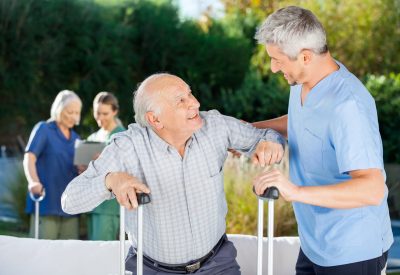 Male And Female Caretakers Helping Elderly People